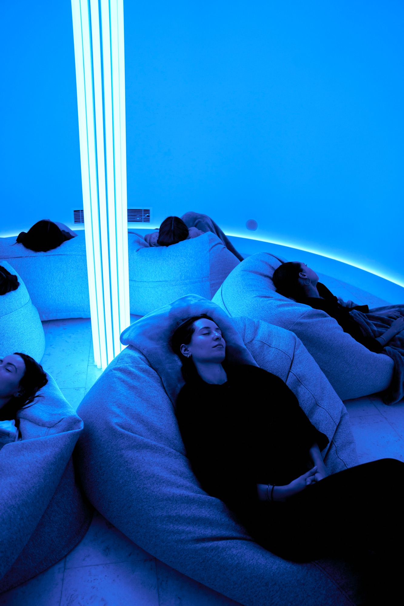 Guests resting on beanbags under blue light inside the EQ dome